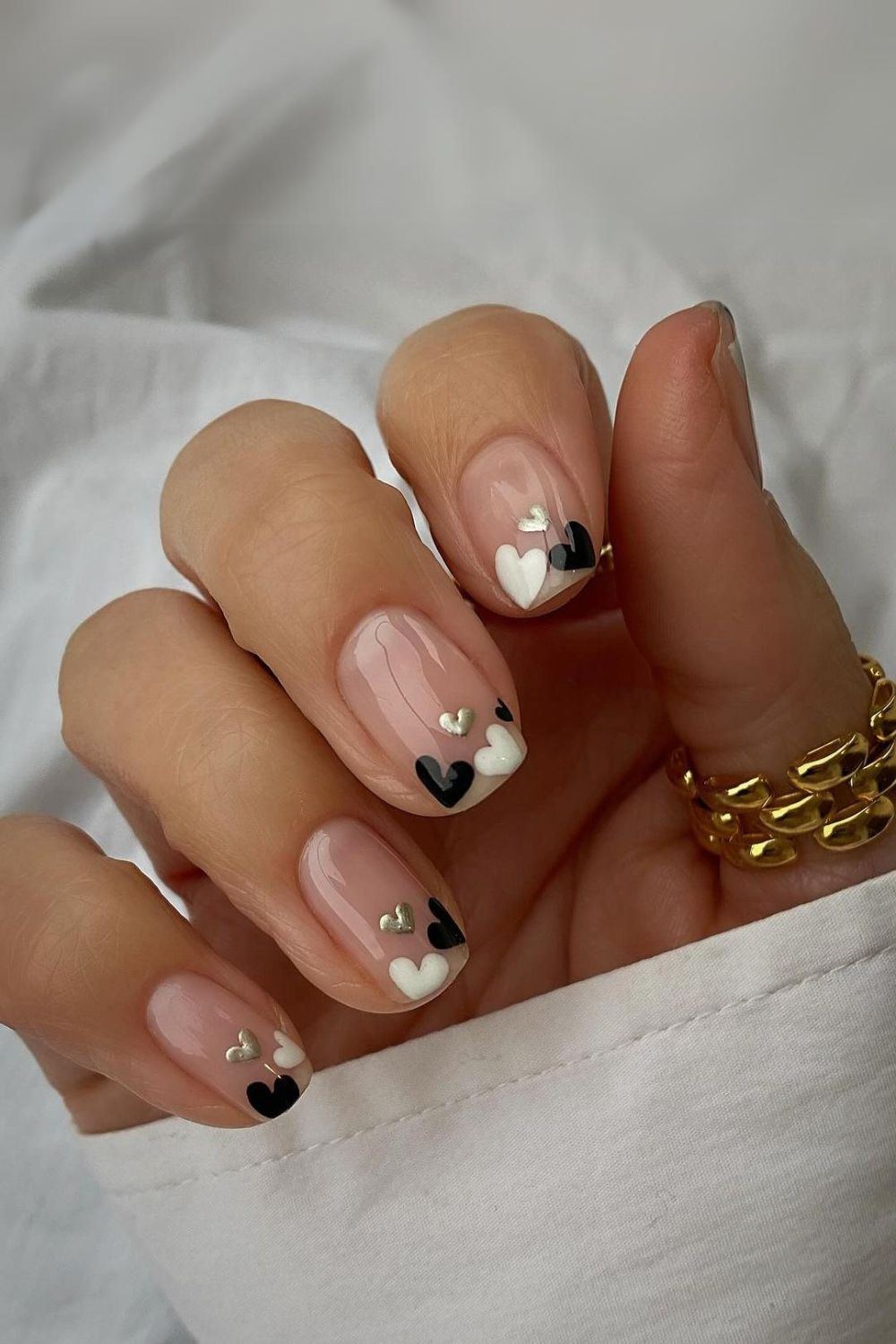 Nude nails with black and white heart accent tips